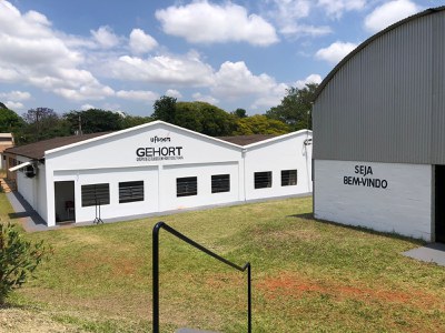 Laboratório do GEHORT - Grupo de Estudos em Horticultura. Se assemelha a uma casa, com o nome do grupo e logotipo da UFSCar na parte superior. Ao lado direito, um galpão com telhado em formato de arco e na parede a mensagem “Seja Bem Vindo”; no chão, o gramado.